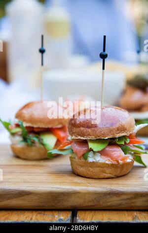 Burger mit Frischkäse, gesalzenem Lachs, Grünkohl, Avocado auf Weizenbun. Rustikaler Hintergrund. Stockfoto