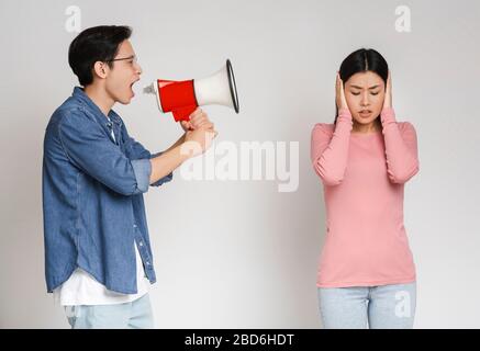 Wütende asien-kerl schreit durch Megafon auf seine Freundin Stockfoto