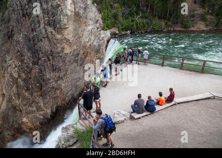 YELLOWSTONE NATIONAL PARK, USA - 12. Juli 2014: Touristen stehen und sitzen auf einem Aussichtspunkt am Gipfel der Lower Falls im Yellowstone River in Yellowston Stockfoto