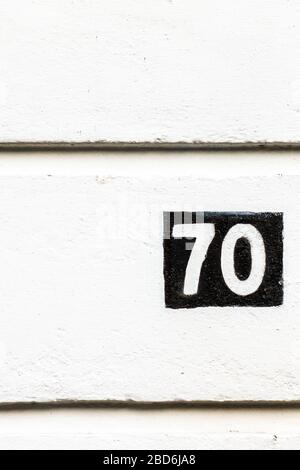 Hausnummer 70 invertiert auf eine Hauswand gemalt Stockfoto