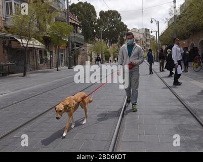 Jerusalem, Israel. April 2020. Ein Israelin trägt eine Maske zum Schutz vor dem Coronavirus, während er seinen Hund am Dienstag, den 7. April 2020 in Jerusalem spaziert. Foto von Debbie Hill/UPI Credit: UPI/Alamy Live News Stockfoto
