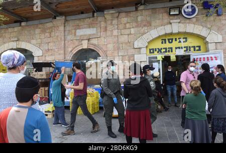 Jerusalem, Israel. April 2020. Israelische Grenzpolizei patrouilliert zwischen Menschen, die wegen Coronavirus-Beschränkungen auf den Eintritt in einen Supermarkt warten, vor dem jüdischen Passahfeiertag am Dienstag, 7. März, in Jerusalem. Der israelische Premierminister Benjamin kündigte strenge Reisebeschränkungen und eine Ausgangssperre für den Passah-Urlaub an, um die Ausbreitung des Coronavirus zu stoppen. Foto von Debbie Hill/UPI Credit: UPI/Alamy Live News Stockfoto