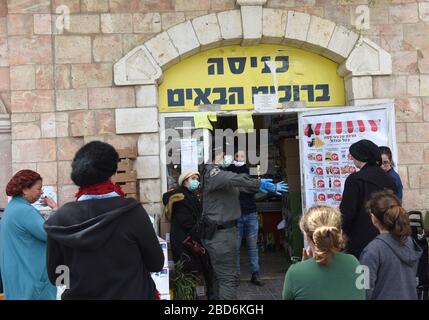 Jerusalem, Israel. April 2020. Eine israelische Grenzpolizei gesteht den Menschen, sich wegen des Coronavirus soziale Distanz zu halten, während sie warten, einen Supermarkt zu betreten, bevor der jüdische Passah-Urlaub am Dienstag, 7. März, in Jerusalem stattfindet. Der israelische Premierminister Benjamin kündigte strenge Reisebeschränkungen und eine Ausgangssperre für den Passah-Urlaub an, um die Ausbreitung des Coronavirus zu stoppen. Foto von Debbie Hill/UPI Credit: UPI/Alamy Live News Stockfoto