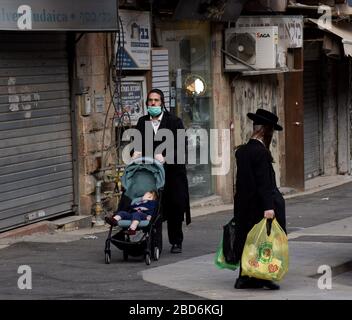 Jerusalem, Israel. April 2020. Ein ultraorthodoxe Jude trägt am Dienstag, 7. März, in Mea Shearim in Jerusalem eine Maske als Schutz vor dem Coronavirus und drückt dabei eine Babykutsche. Der israelische Premierminister Benjamin kündigte strenge Reisebeschränkungen und eine Ausgangssperre für den Passah-Urlaub an, um die Ausbreitung des Coronavirus zu stoppen. Foto von Debbie Hill/UPI Credit: UPI/Alamy Live News Stockfoto