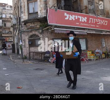 Jerusalem, Israel. April 2020. Ultra-orthodoxe Juden tragen Masken und Handschuhe, als Schutz vor dem Coronavirus, während sie am Dienstag, 7. März, in Mea Shearim, Jerusalem nach dem jüdischen Feiertag Passah einkaufen. Der israelische Premierminister Benjamin kündigte strenge Reisebeschränkungen und eine Ausgangssperre für den Passah-Urlaub an, um die Ausbreitung des Coronavirus zu stoppen. Foto von Debbie Hill/UPI Credit: UPI/Alamy Live News Stockfoto