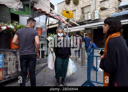 Jerusalem, Israel. April 2020. Eine israelische Frau trägt eine Maske und Handschuhe, als Schutz vor dem Coronavirus, während sie am Dienstag, den 7. März, in Jerusalem für den jüdischen Feiertag Passah auf dem Mahane Yehuda-Markt einkauft. Der israelische Premierminister Benjamin kündigte strenge Reisebeschränkungen und eine Ausgangssperre für den Passah-Urlaub an, um die Ausbreitung des Coronavirus zu stoppen. Foto von Debbie Hill/UPI Credit: UPI/Alamy Live News Stockfoto