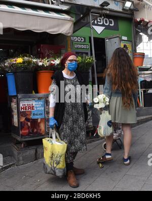 Jerusalem, Israel. April 2020. Eine israelische Frau trägt eine Maske und Handschuhe, als Schutz vor dem Coronavirus, während sie am Dienstag, den 7. März, in Jerusalem für den jüdischen Feiertag Passah auf dem Mahane Yehuda-Markt einkauft. Der israelische Premierminister Benjamin kündigte strenge Reisebeschränkungen und eine Ausgangssperre für den Passah-Urlaub an, um die Ausbreitung des Coronavirus zu stoppen. Foto von Debbie Hill/UPI Credit: UPI/Alamy Live News Stockfoto