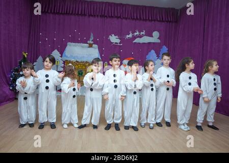 Die Kinder sind als Schneemänner verkleidet. Kindergartenteilnehmer nehmen an einer Neujahrsveranstaltung Teil. Niedliche Jungen in festlichen Kostümen des Weihnachtsmanns Stockfoto