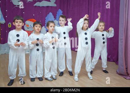 Die Kinder sind als Schneemänner verkleidet. Kindergartenteilnehmer nehmen an einer Neujahrsveranstaltung Teil. Niedliche Jungen in festlichen Kostümen des Weihnachtsmanns Stockfoto