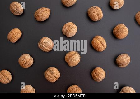 Muster geschälte Walnüsse in einer Reihe auf schwarzem Hintergrund. Draufsicht. Stockfoto