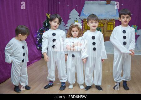 Die Kinder sind als Schneemänner verkleidet. Kindergartenteilnehmer nehmen an einer Neujahrsveranstaltung Teil. Niedliche Jungen in festlichen Kostümen des Weihnachtsmanns Stockfoto