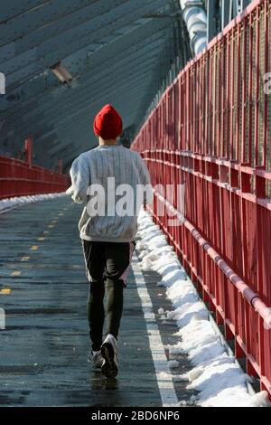 Mann in roter Mütze joggt entlang der Williamsburg Bridge in New York City, USA Stockfoto