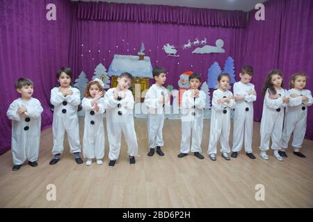 Die Kinder sind als Schneemänner verkleidet. Kindergartenteilnehmer nehmen an einer Neujahrsveranstaltung Teil. Niedliche Jungen in festlichen Kostümen des Weihnachtsmanns Stockfoto