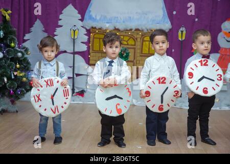 Die Kinder . Kindergartenteilnehmer nehmen an einer Neujahrsveranstaltung Teil. Niedliche Jungs in festlichen Kostümen des Anzugs. Fröhliches Kind mit großem Festhalten Stockfoto