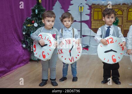 Die Kinder . Kindergartenteilnehmer nehmen an einer Neujahrsveranstaltung Teil. Niedliche Jungs in festlichen Kostümen des Anzugs. Fröhliches Kind mit großem Festhalten Stockfoto