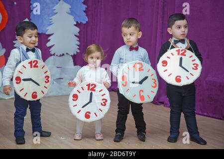 Die Kinder . Kindergartenteilnehmer nehmen an einer Neujahrsveranstaltung Teil. Niedliche Jungs in festlichen Kostümen des Anzugs. Fröhliches Kind mit großem Festhalten Stockfoto