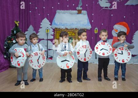 Die Kinder . Kindergartenteilnehmer nehmen an einer Neujahrsveranstaltung Teil. Niedliche Jungs in festlichen Kostümen des Anzugs. Fröhliches Kind mit großem Festhalten Stockfoto