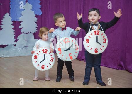 Die Kinder . Kindergartenteilnehmer nehmen an einer Neujahrsveranstaltung Teil. Niedliche Jungs in festlichen Kostümen des Anzugs. Fröhliches Kind mit großem Festhalten Stockfoto