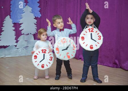 Die Kinder . Kindergartenteilnehmer nehmen an einer Neujahrsveranstaltung Teil. Niedliche Jungs in festlichen Kostümen des Anzugs. Fröhliches Kind mit großem Festhalten Stockfoto