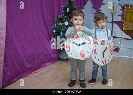 Die Kinder . Kindergartenteilnehmer nehmen an einer Neujahrsveranstaltung Teil. Niedliche Jungs in festlichen Kostümen des Anzugs. Fröhliches Kind mit großem Festhalten Stockfoto