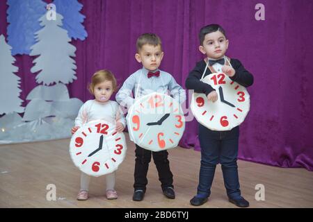 Die Kinder . Kindergartenteilnehmer nehmen an einer Neujahrsveranstaltung Teil. Niedliche Jungs in festlichen Kostümen des Anzugs. Fröhliches Kind mit großem Festhalten Stockfoto