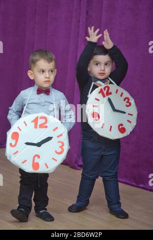 Die Kinder . Kindergartenteilnehmer nehmen an einer Neujahrsveranstaltung Teil. Niedliche Jungs in festlichen Kostümen des Anzugs. Fröhliches Kind mit großem Festhalten Stockfoto