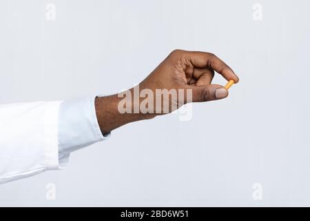 Nahaufnahme der schwarzen Arzthand mit einer einzigen Tablette Stockfoto