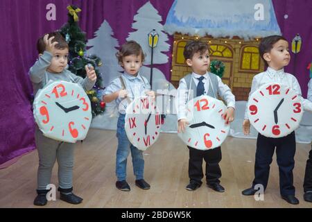 Die Kinder . Kindergartenteilnehmer nehmen an einer Neujahrsveranstaltung Teil. Niedliche Jungs in festlichen Kostümen des Anzugs. Fröhliches Kind mit großem Festhalten Stockfoto