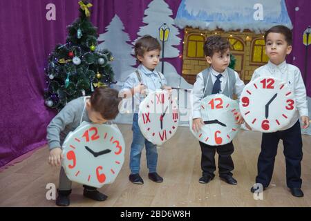 Die Kinder . Kindergartenteilnehmer nehmen an einer Neujahrsveranstaltung Teil. Niedliche Jungs in festlichen Kostümen des Anzugs. Fröhliches Kind mit großem Festhalten Stockfoto