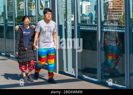 Melbourne Australia - 10. März 2019; asiatisches Touristenpaar auf Sandridge Fußgängerbrücke, das an den riesigen Edelstahlskulpturen und Glasscheiben vorbeigeht Stockfoto