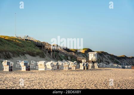 Deutsches Strandresort mit Korbstühlen, in morgendlichem Sonnenlicht bewachsene Dünen auf der Sylter Insel an der Nordsee. Ziel. Stockfoto