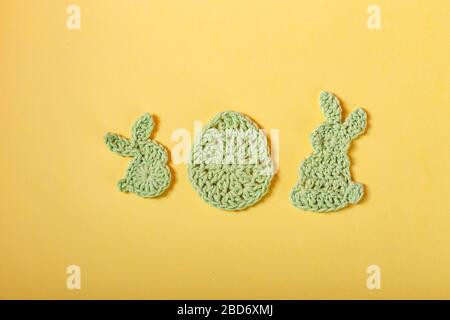 Frohe Ostern. Osterdekoration, bunte rabbitsand Eier aus gehäckseltem buntem Garn auf gelbem Hintergrund. Hausgemachte Einrichtung. Draufsicht. Frühlings-Ostern Stockfoto