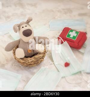 Spielzeugwelpe selbstisoliert in einem Nest unter medizinischen Masken und einem individuellen Erste-Hilfe-Kit, Gesundheitskonzept Stockfoto
