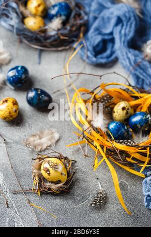 Farbige gelbe und blaue Osterquageleier in kleinen Nestern. Wachteleier für katholische und orthodoxe osterfeiertage. Geringe Schärfentiefe. Stockfoto