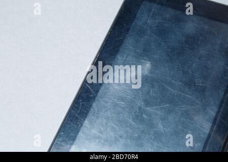 Schwarz verkratztes Tablett mit einer Schutzfolie auf grauem Hintergrund. Schützen Sie den Bildschirm Ihres Geräts Stockfoto