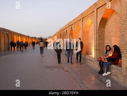 Menschen, die auf der Allahverdi Khan Bridge (Si-o-SE Pol 33 Arches Bridge) über den Fluss Zayandeh, Isfahan, Provinz Esfahan, Iran, Mitte E spazieren und sitzen Stockfoto