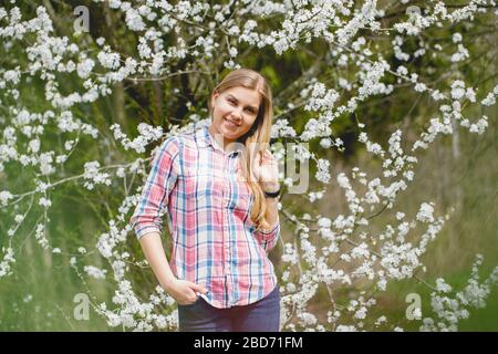 Schönes Mädchen in blühenden Bäumen im Frühjahr. Helle Sonne und Natur Stockfoto