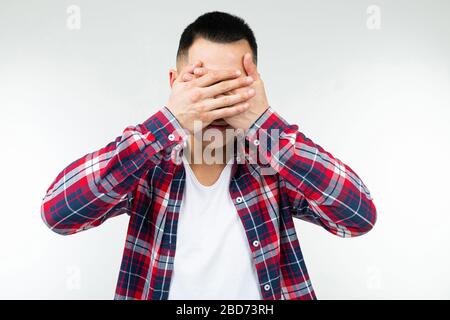 Asian Guy in einem karierten Hemd weit geöffnet schließt seine Augen auf einem isolierten weißen Studiohintergrund Stockfoto