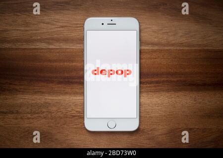 Ein iPhone mit dem Depop-Logo ruht auf einem einfachen Holztisch (nur für redaktionelle Verwendung). Stockfoto