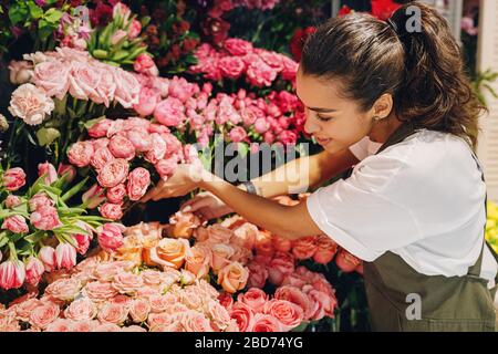 Junge Frau, die in einem Blumenladen arbeitet. Blumenfrau wählt Blumen. Stockfoto