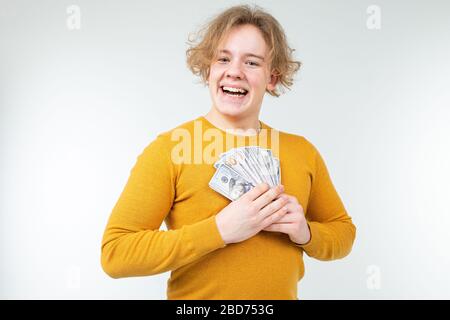 Glücklicher blonder Kerl hält sein Gehalt auf weißem Hintergrund Stockfoto