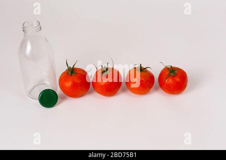 Frische mediterrane Tomaten auf weißem Hintergrund mit leerem Glas. Stockfoto