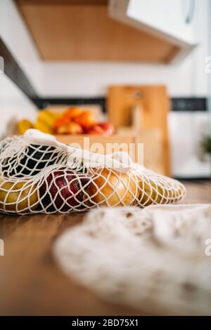 Einige Obst- und Gemüsesorten in einer wiederverwendbaren Netztasche aus biologischer Baumwolle auf Holzhintergrund. Kein Abfall, Kunststofffreies Konzept. Nachhaltiger Lebensstil. Stockfoto