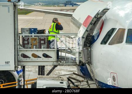 FLUGHAFEN LONDON-GATWICK, ENGLAND - APRIL 2019: Person, die einen Airbus Jet von British Airways mit in Flight Catering Versorgungsgütern auf dem Flughafen London-Gatwick lädt Stockfoto