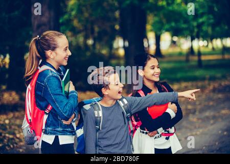 Zurück zur Schule. Schließen Sie drei glückliche Freunde mit Rucksäcken, die lachen und Spaß im Park haben. Junge und Mädchen, die am ersten Schultag Bücher halten. K Stockfoto