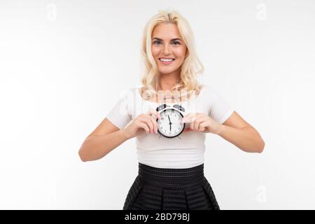 Emotionales Mädchen in einem weißen T-Shirt hält eine Uhr auf weißem Hintergrund mit Kopierraum Stockfoto