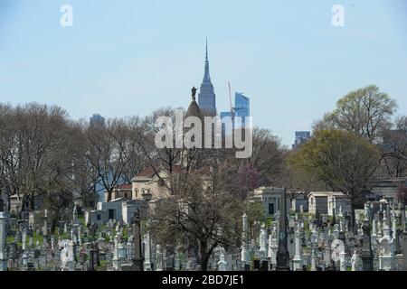 New York Queens, USA. April 2020. Die Skyline von NYC hinter dem Calvary Cemetery ist ein Roman-katholischer Friedhof. Leichensystem ist überfordert. Morgues, Krankenhäuser, Bestattungsunternehmen, Friedhöfe und Krematorien. Die Zahl der COVID-19-Todesopfer in der NYC beträgt 3.324 und 72.324 bestätigte Fälle. 04/07/20. New York Queens Saint John Friedhof. Kredit: Marcus Santos/ZUMA Wire/Alamy Live News Stockfoto