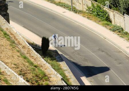 Ein einzelner Radfahrer, der auf einer einsamen Straße radelt Stockfoto