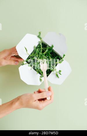 Frau, die Erbsen mit Bambusgabel aus der Papierbox isst. Nur Hände Stockfoto