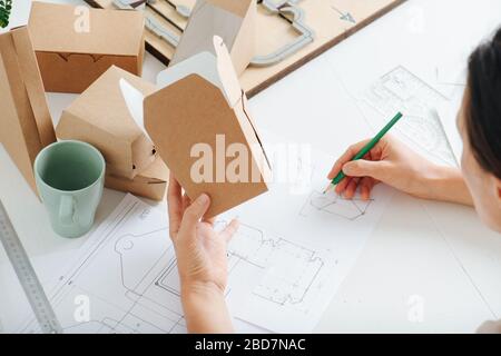 Boxenhersteller, die hinter einem Tisch arbeiten und die Box in der Hand halten Stockfoto